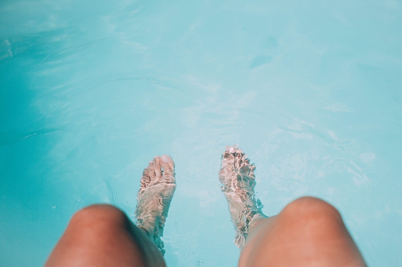 Immagine di due piedi immersi nell'acqua cristallina della piscina dopo l'apertura estiva.